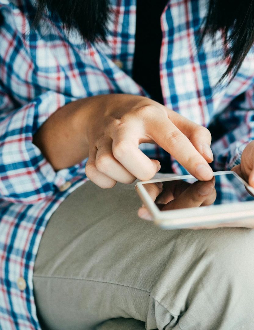 personne vêtue d'une chemise à carreaux sur son smartphone